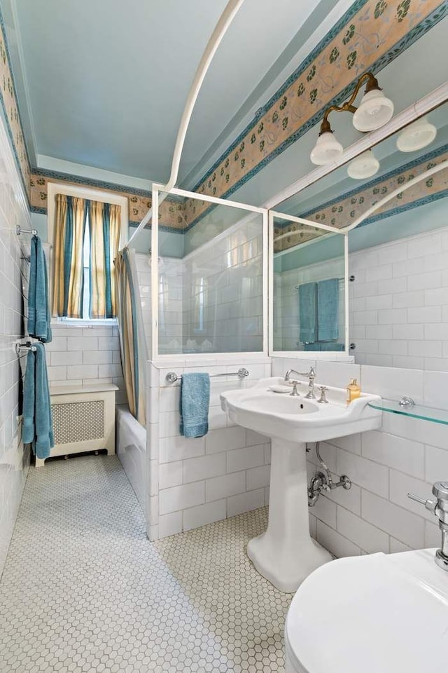full bath with tile patterned floors, tile walls, radiator, and tiled shower / bath
