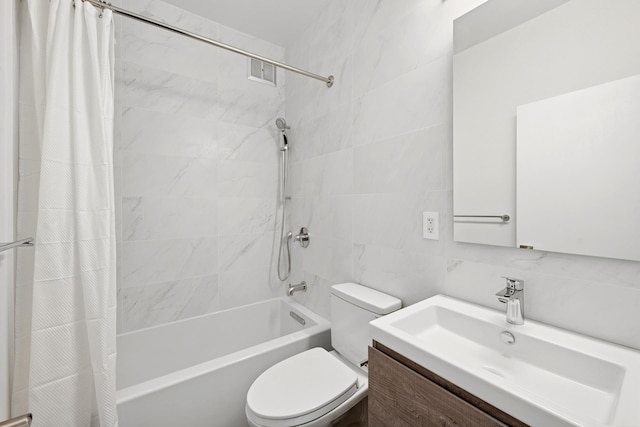 bathroom with tile walls, vanity, toilet, and shower / tub combo
