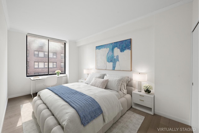 bedroom featuring baseboards, ornamental molding, and wood finished floors
