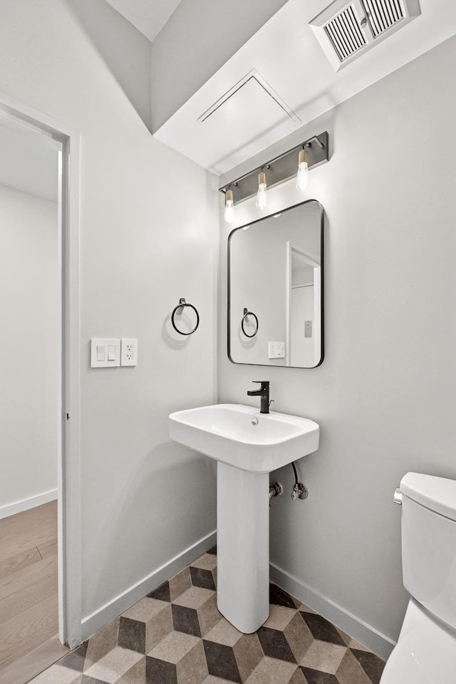 half bath featuring visible vents, baseboards, and toilet