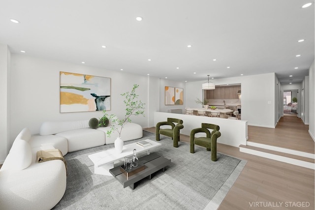 living room with recessed lighting, baseboards, and light wood-type flooring