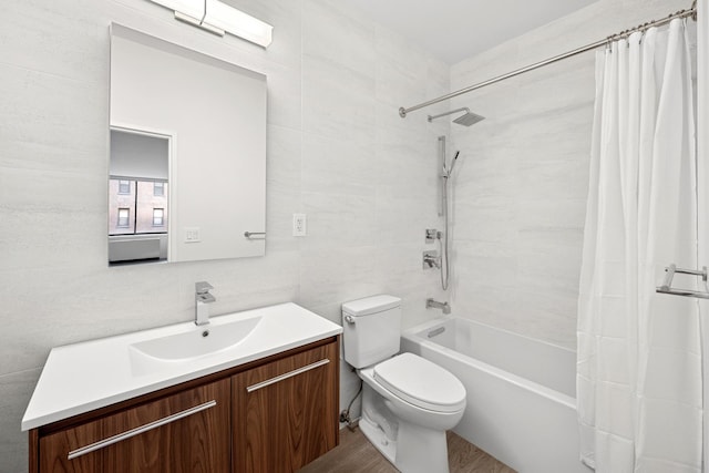 bathroom with vanity, shower / tub combo with curtain, wood finished floors, toilet, and tile walls