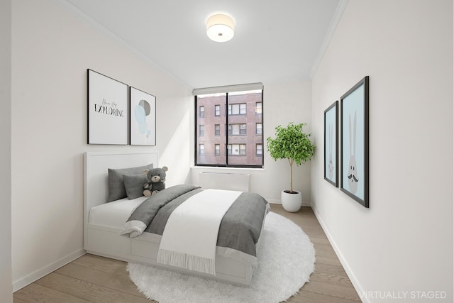 bedroom featuring baseboards, ornamental molding, and wood finished floors