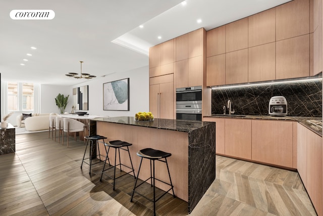 kitchen featuring visible vents, modern cabinets, a sink, a kitchen island, and a breakfast bar area
