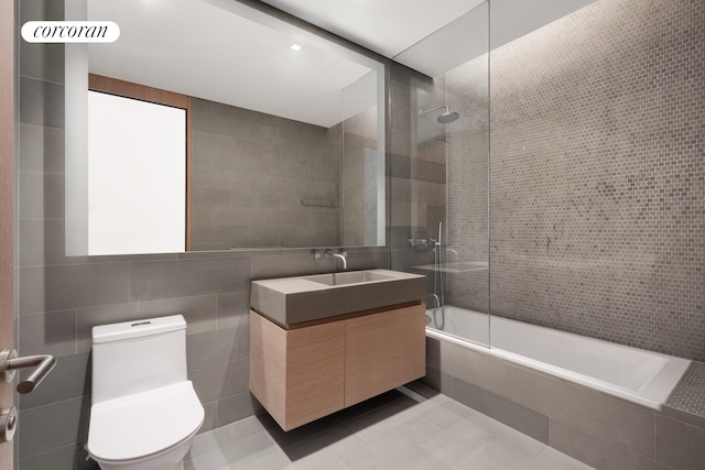 bathroom with tiled shower / bath combo, tile walls, tile patterned flooring, and toilet