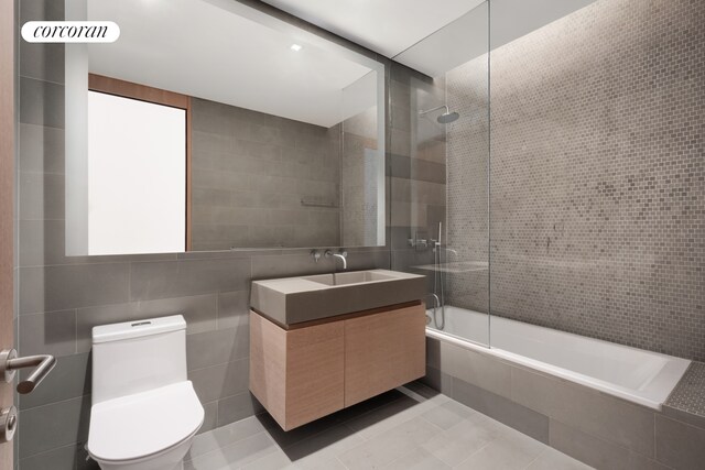 49 Chambers St Unit 5D, New York City, NY 10007 - bathroom with tile walls, toilet, tiled shower / bath combo, vanity, and tile patterned floors