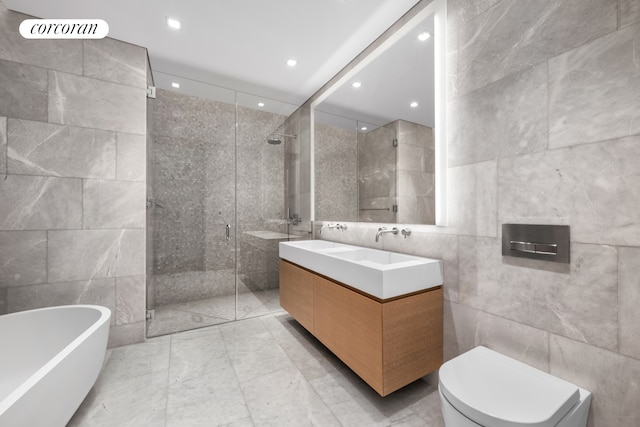 full bathroom with tile walls, a freestanding bath, double vanity, and a stall shower