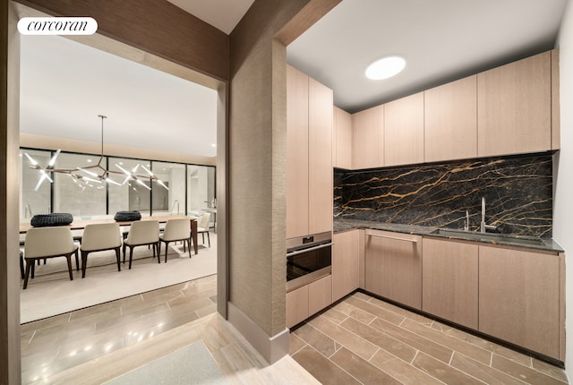 kitchen with a sink, stainless steel oven, dark countertops, visible vents, and backsplash