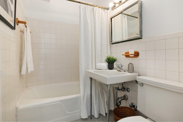 bathroom featuring shower / tub combo, toilet, a sink, and tile walls