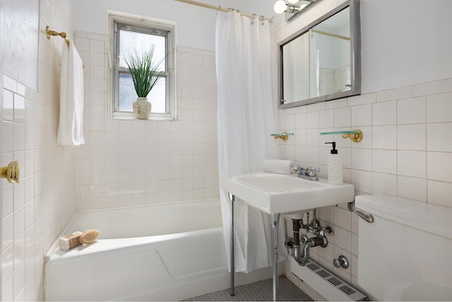 bathroom featuring toilet, shower / bath combo with shower curtain, and tile walls
