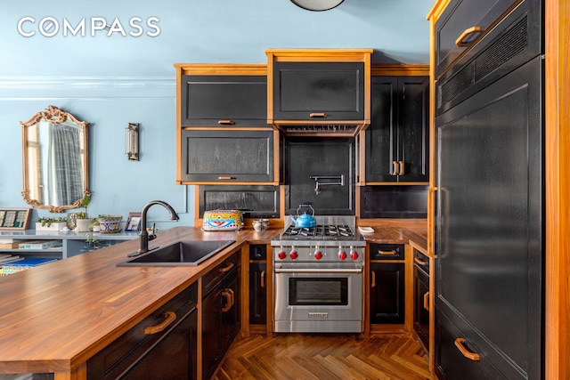 kitchen featuring refrigerator, premium range, a sink, wooden counters, and a peninsula