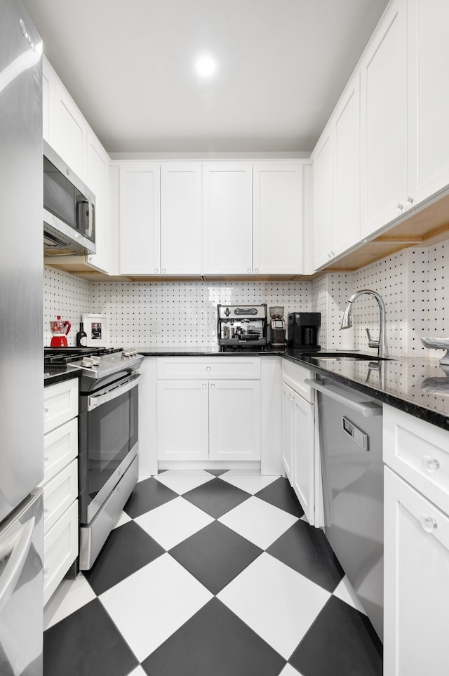 130 E 94th St Unit 5-E, New York City, NY 10128 - kitchen featuring appliances with stainless steel finishes, tile patterned floors, white cabinets, dark countertops, and backsplash