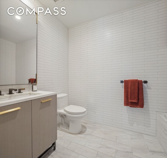 bathroom with tile walls, toilet, and vanity