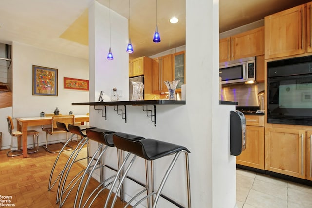 3850 Hudson Manor Ter Unit 1Ee/2Ee, New York City, NY 10463 - kitchen with stainless steel microwave, oven, a kitchen bar, dark countertops, and refrigerator