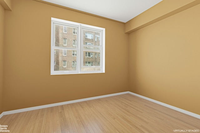 spare room featuring light wood finished floors and baseboards