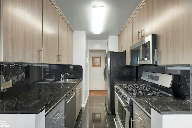 kitchen featuring dark tile patterned floors, stainless steel appliances, light brown cabinetry, and a sink