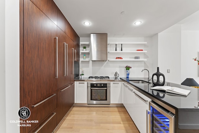 kitchen featuring range hood, open shelves, a sink, wine cooler, and oven