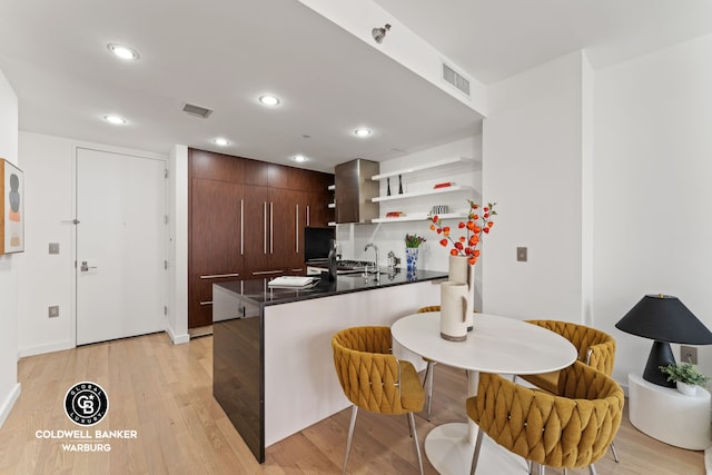 kitchen featuring a peninsula, open shelves, visible vents, and a sink