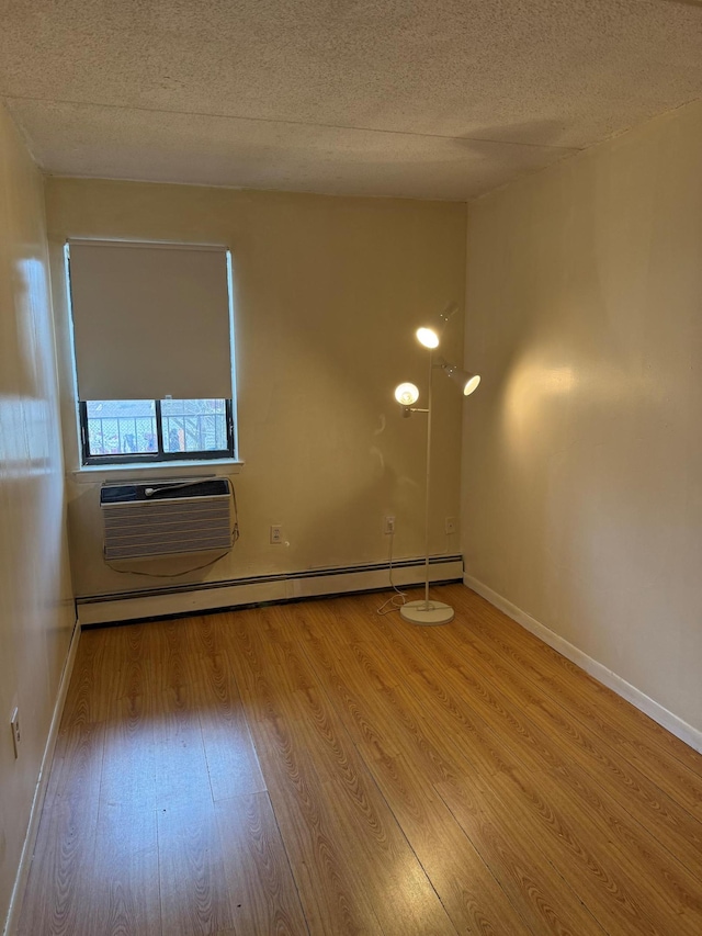 spare room with wood finished floors, a textured ceiling, and a wall unit AC