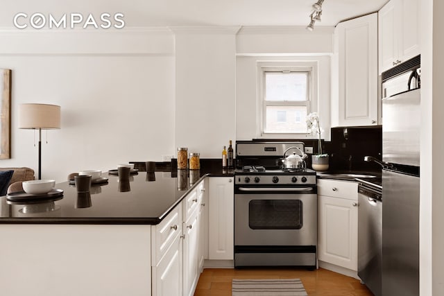 330 E 49th St Unit 9C, New York City, NY 10017 - kitchen featuring appliances with stainless steel finishes, a peninsula, dark countertops, white cabinets, and crown molding