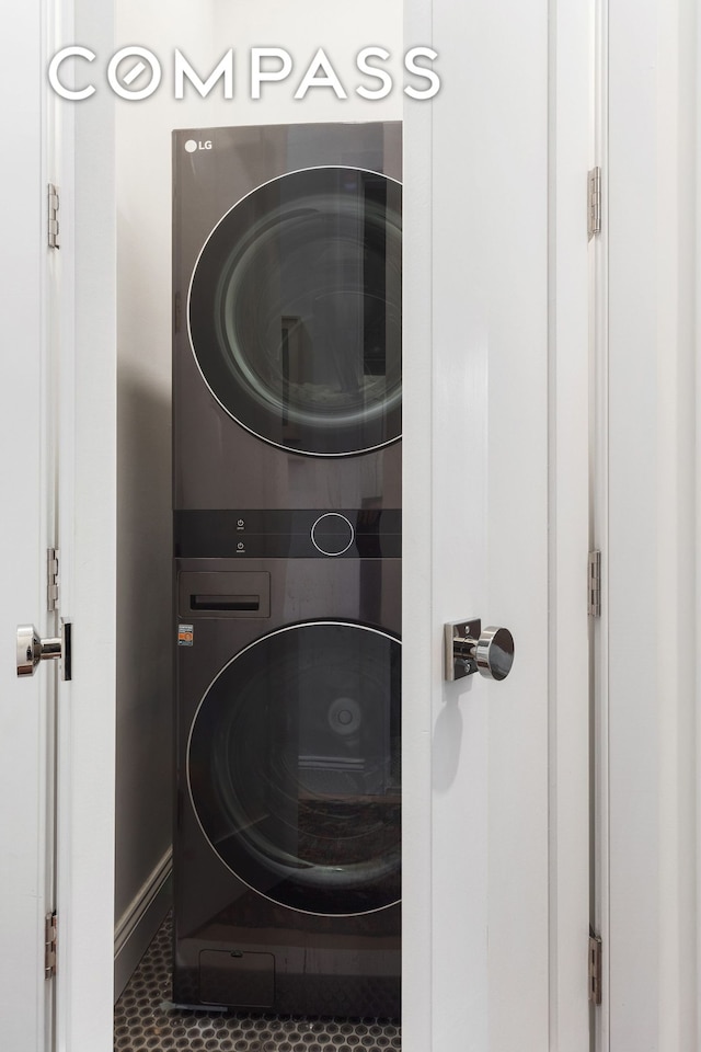 washroom with stacked washing machine and dryer, baseboards, and tile patterned floors