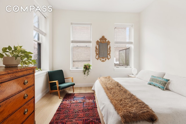 bedroom featuring multiple windows, light wood finished floors, and baseboards