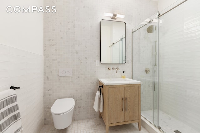 bathroom with tile walls, a stall shower, vanity, tile patterned flooring, and toilet