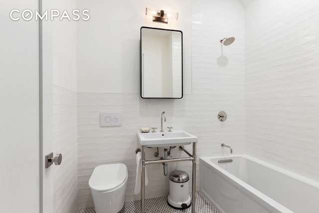 full bathroom featuring tile walls, a sink, tile patterned flooring, toilet, and shower / washtub combination