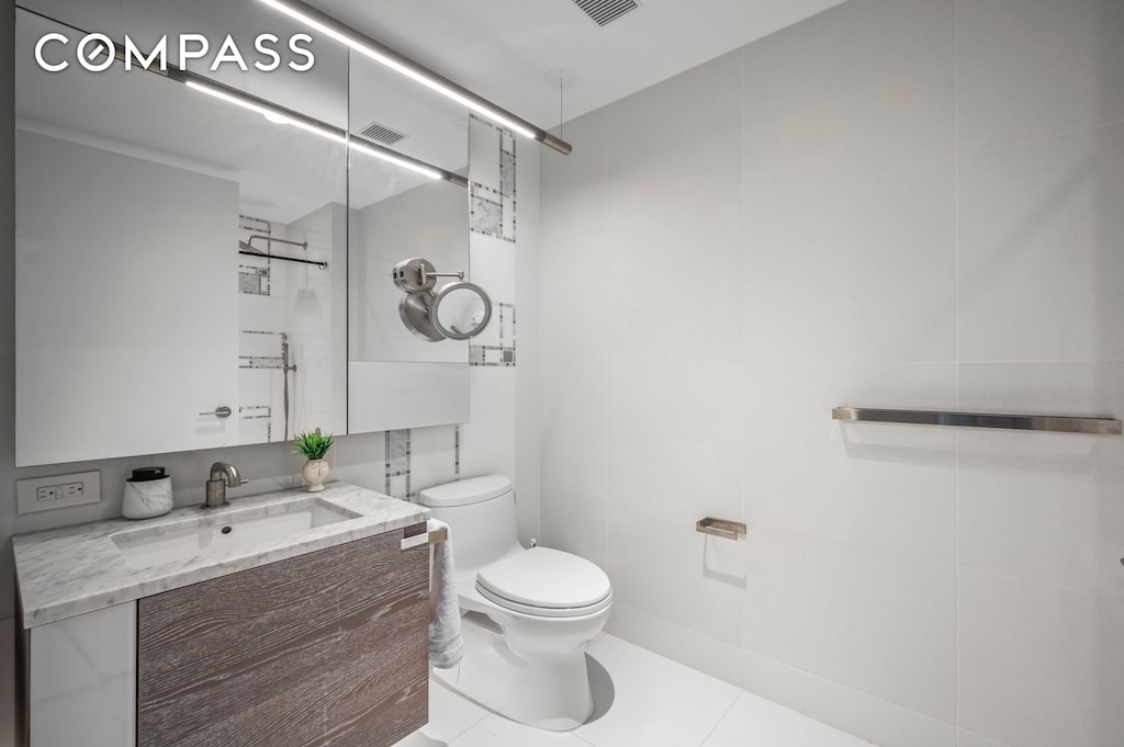 bathroom with visible vents, tile walls, tile patterned flooring, vanity, and toilet