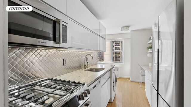 100 W 93rd St Unit 8K, New York City, NY 10025 - kitchen with appliances with stainless steel finishes, washer / dryer, white cabinetry, and tasteful backsplash