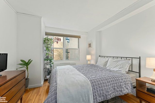 bedroom with ornamental molding and light wood-style flooring