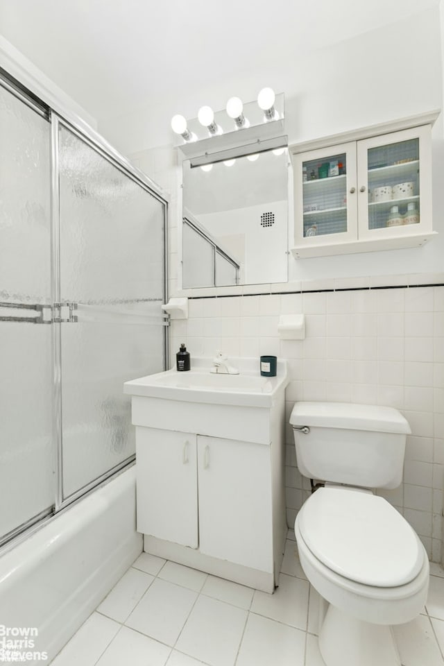 full bathroom featuring tile walls, tile patterned floors, vanity, toilet, and enclosed tub / shower combo