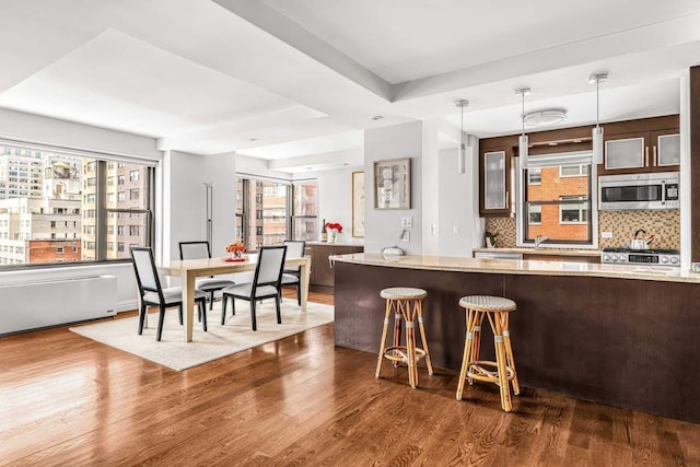 55 E End Ave Unit 12Hj, New York City, NY 10028 - kitchen featuring tasteful backsplash, glass insert cabinets, stainless steel microwave, and dark wood finished floors