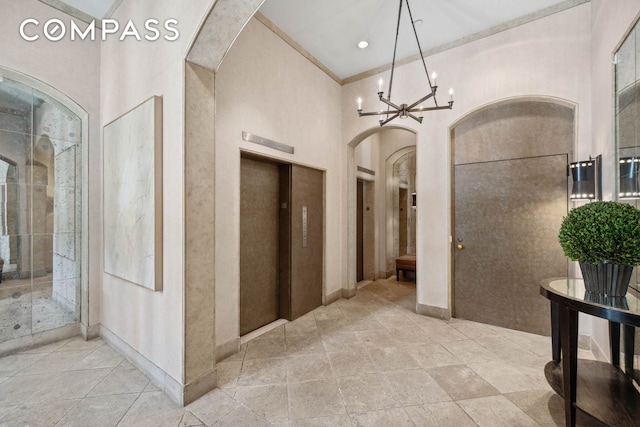 hallway with arched walkways, elevator, baseboards, a chandelier, and a high ceiling