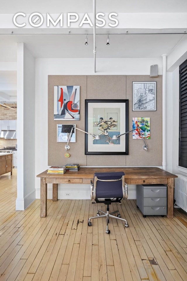 office area with built in study area, radiator, and wood-type flooring