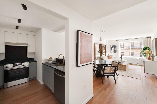 603 W 148th St Unit 3A, New York City, NY 10031 - kitchen featuring stainless steel appliances, a sink, dark countertops, and light wood-style flooring