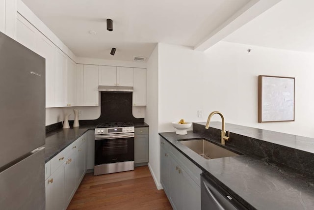 603 W 148th St Unit 3A, New York City, NY 10031 - kitchen featuring appliances with stainless steel finishes, a sink, white cabinets, light wood finished floors, and dark stone countertops