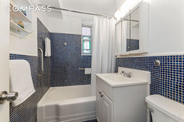 39-30 52nd St Unit 5E, New York City, NY 11377 - bathroom featuring tile walls, toilet, vanity, shower / bathtub combination with curtain, and a wainscoted wall