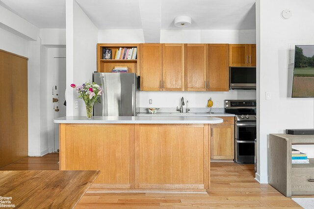 2166 Broadway Unit 16F, New York City, NY 10024 - kitchen featuring appliances with stainless steel finishes, open shelves, light countertops, light wood-style floors, and a kitchen island