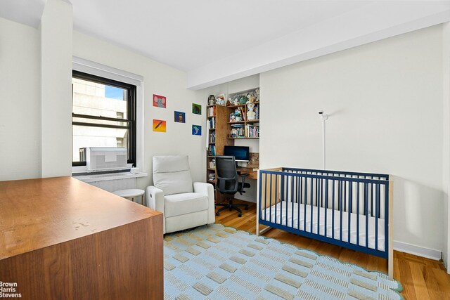 2166 Broadway Unit 16F, New York City, NY 10024 - bedroom featuring wood finished floors, an office area, cooling unit, and a crib