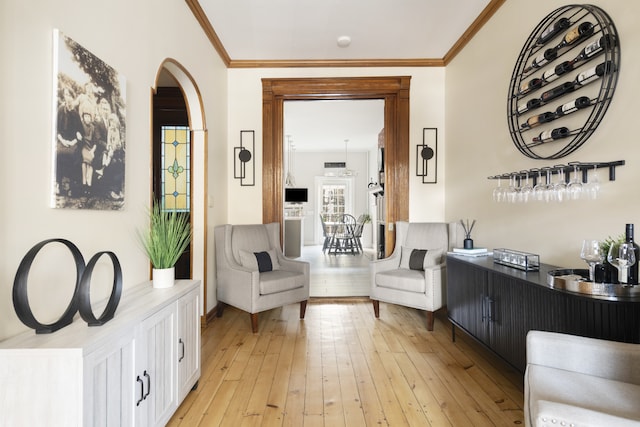 living area with arched walkways, light wood finished floors, crown molding, and baseboards