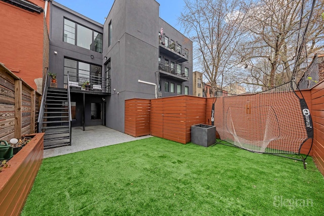 back of property with stucco siding, a lawn, and stairs