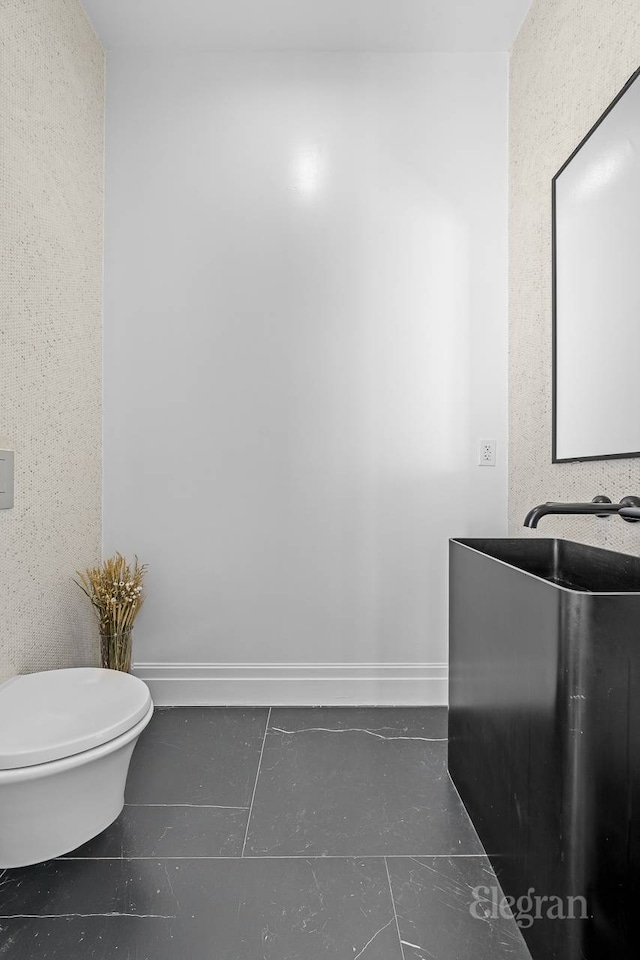 half bath featuring toilet, tile patterned floors, vanity, and baseboards