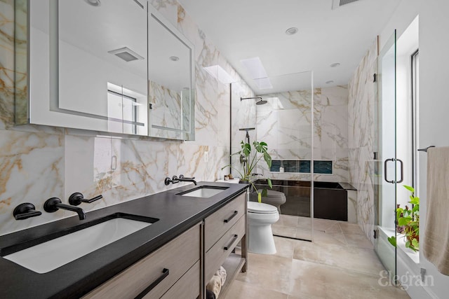 bathroom featuring a sink, toilet, and a marble finish shower