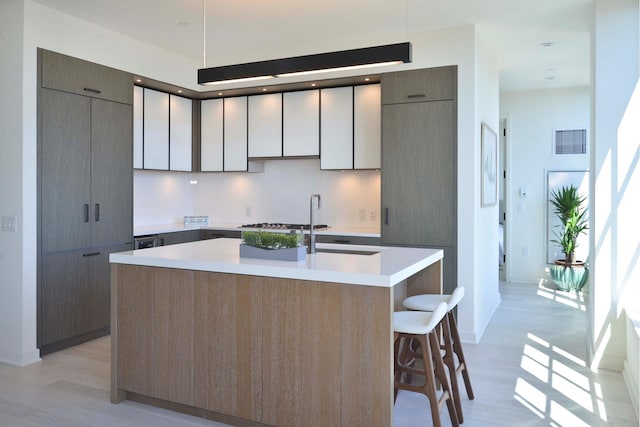 959 1st Ave Unit 25E, New York City, NY 10022 - kitchen with modern cabinets, light wood-style flooring, a kitchen island with sink, and light countertops