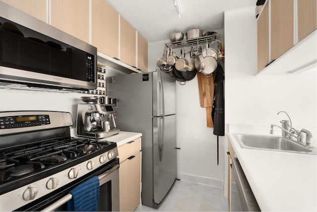 kitchen featuring a sink, light countertops, appliances with stainless steel finishes, and baseboards