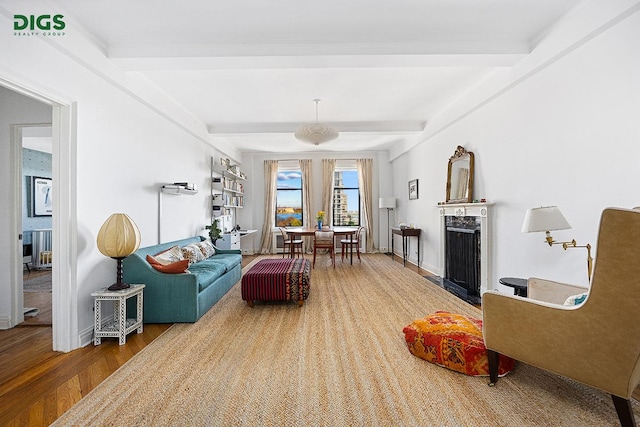 living area featuring beamed ceiling, a fireplace, wood finished floors, and baseboards