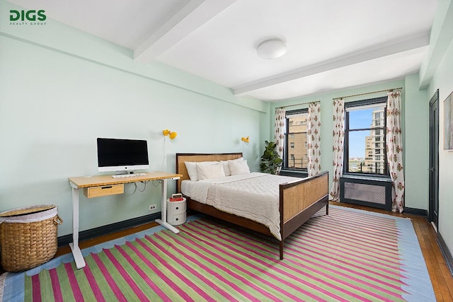 bedroom featuring beamed ceiling, wood finished floors, and baseboards