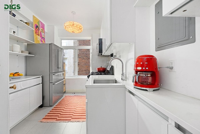 kitchen with freestanding refrigerator, a sink, white cabinets, and light countertops