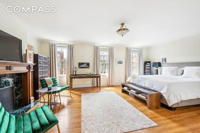 bedroom featuring ornamental molding, wood finished floors, and a high end fireplace